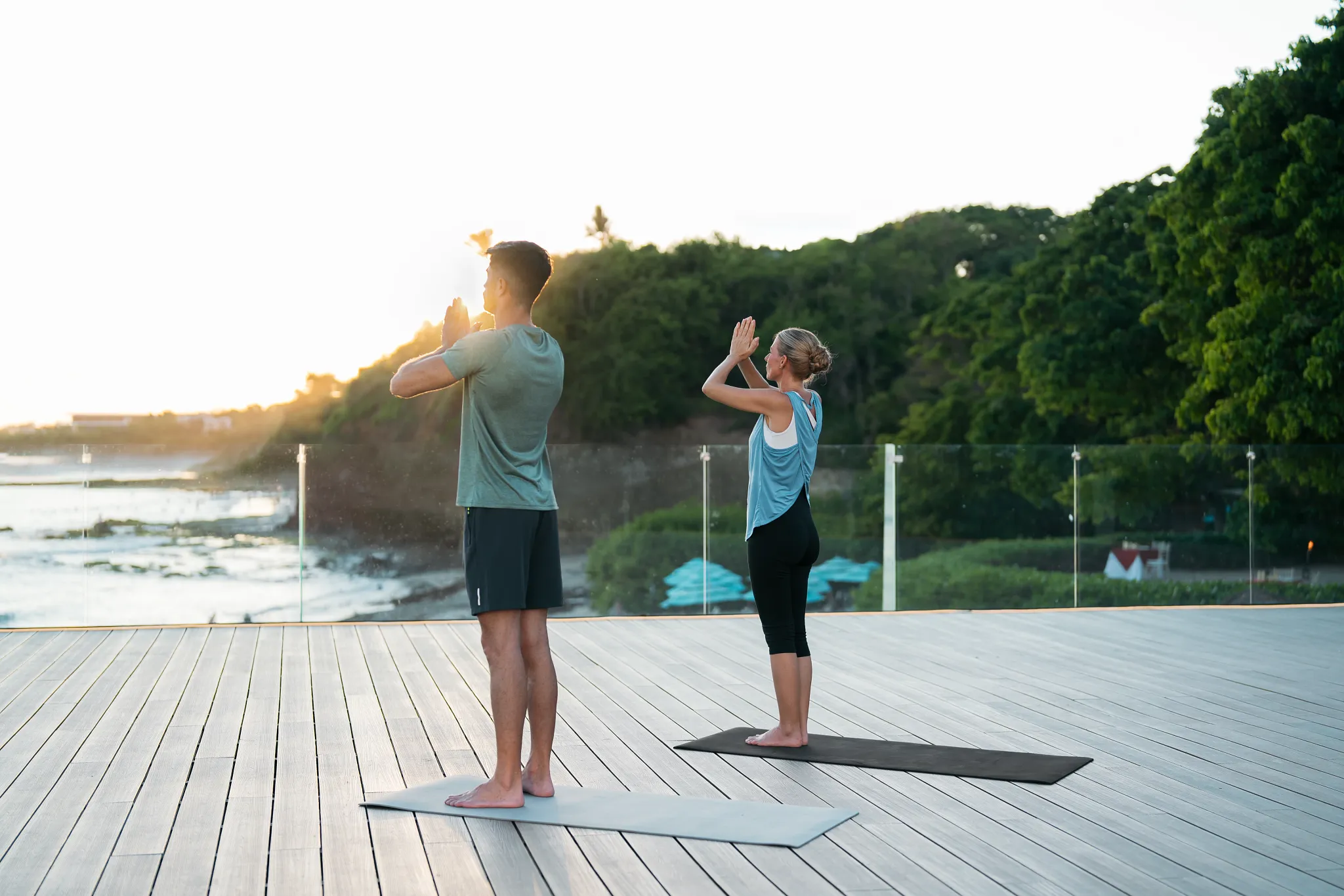 Couple practicing yoga at sunrise on an outdoor deck overlooking the ocean at Dreams Bahia Mita.