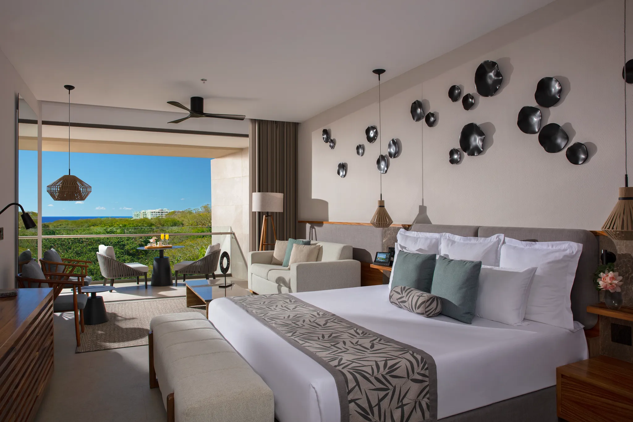 Preferred Club Junior Suite Partial Ocean View with king bed and balcony overlooking greenery and ocean at Dreams Bahia Mita.